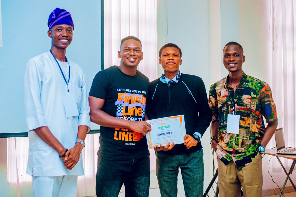 Hunsu Gabriel Boluwatife, third place winner of the 2026 Chidera Anushiem Undergraduate Essay Competition receiving his award at the 2026 Ibadan Boys Conference, flanked by BWB NG co-founders and a representative of partner organization, Writinova